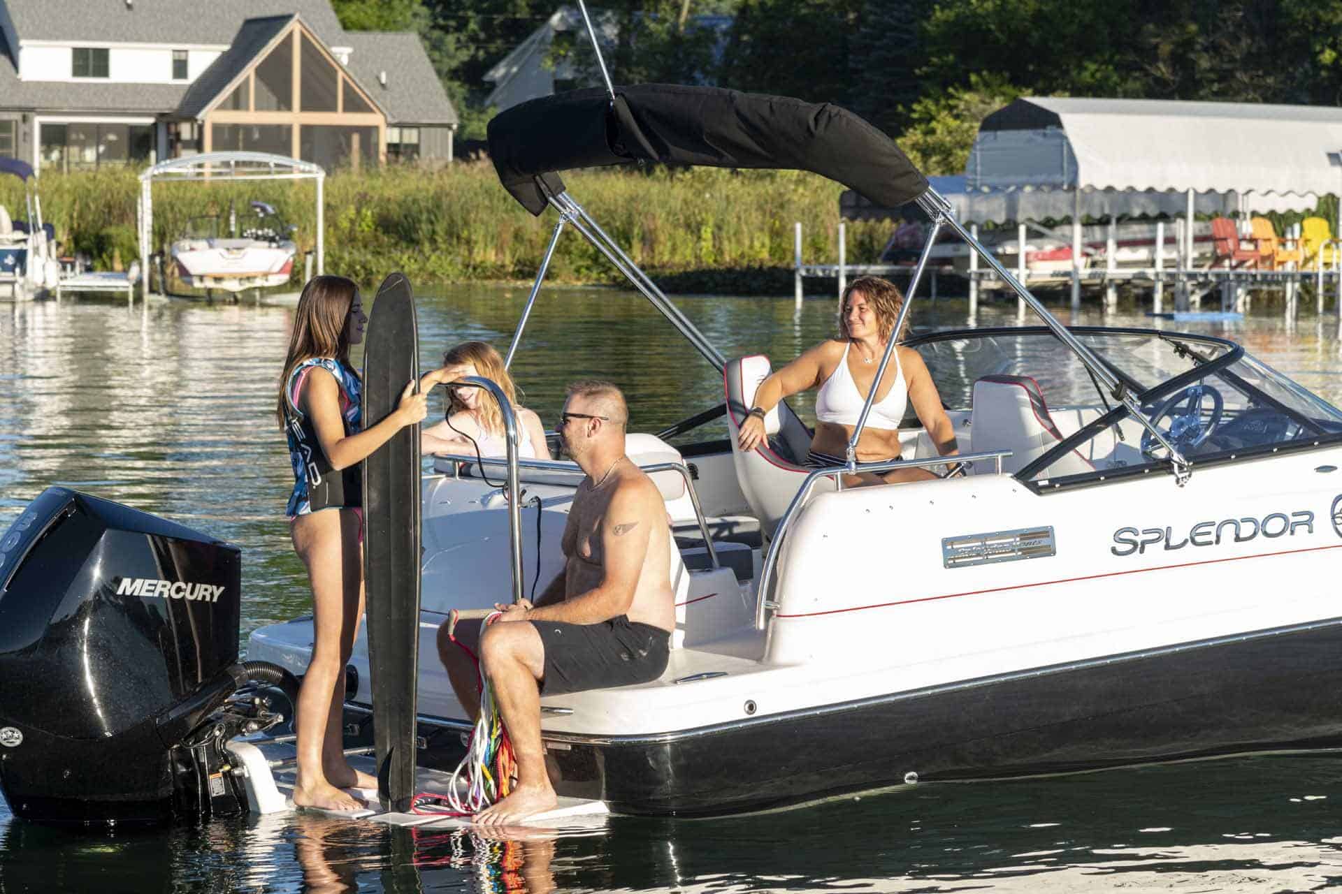 Three people wearing swimsuits sitting on a deck boat built by Splendor Boats.