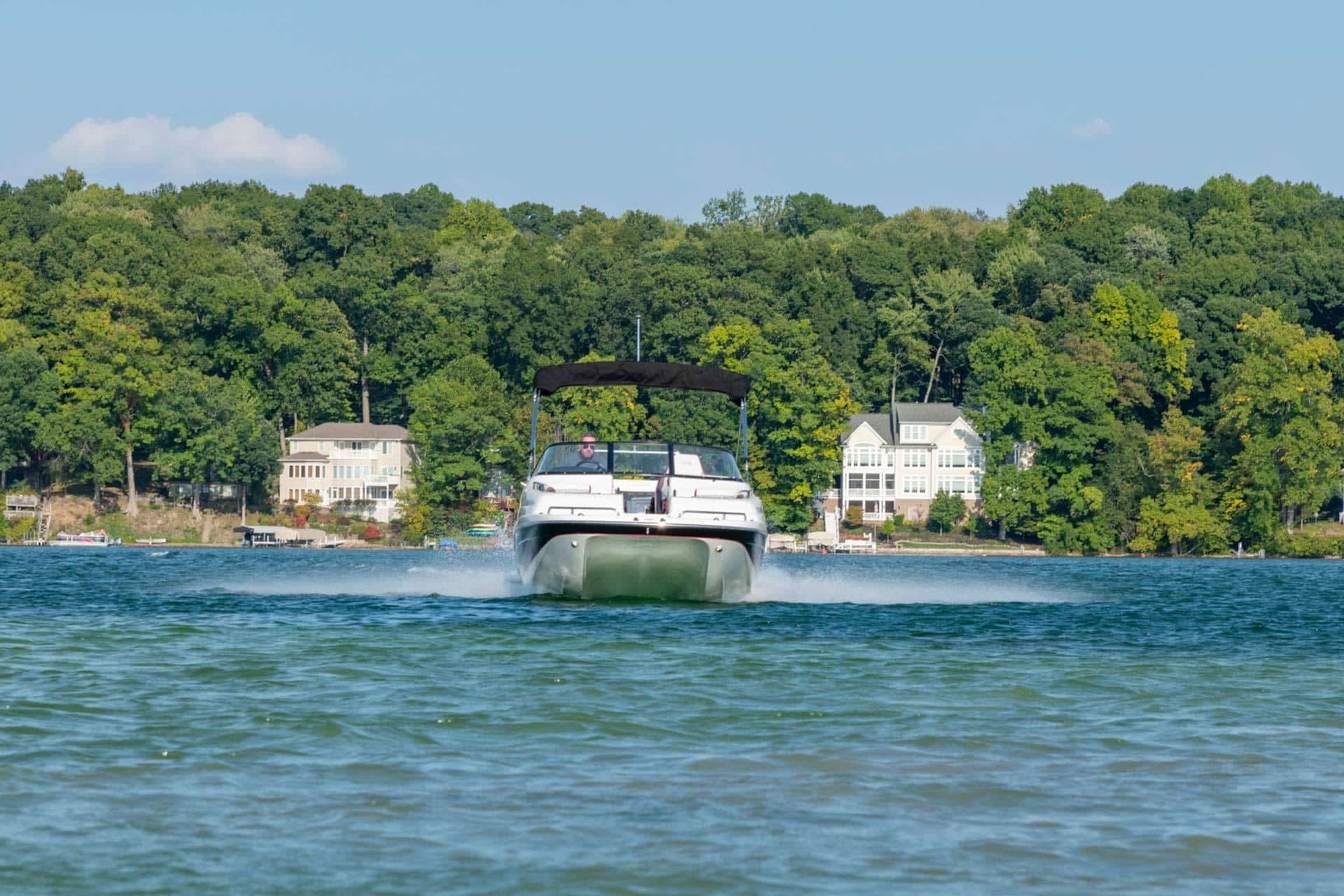 A catamaran deck boat built by Splendor Boats driving straight toward the camera with a small wake behind it.